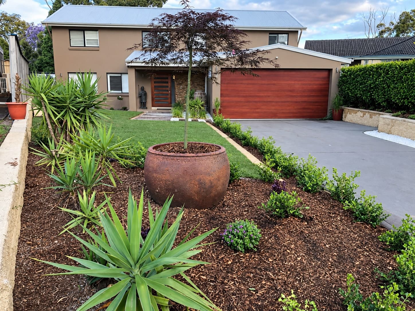 A front garden with a large feature pot, new plants and fresh mulch